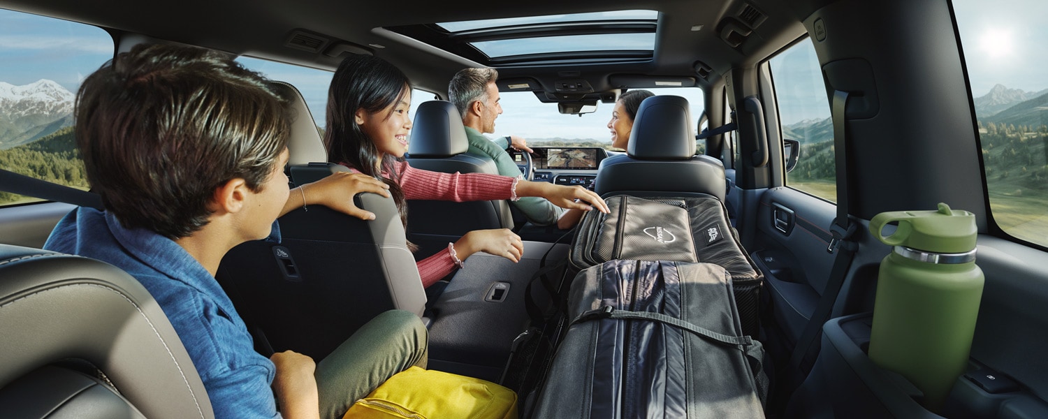 View from the cargo area of a Nissan Armada with a passenger in the back seat and packed with outdoor gear, showing up the spacious interior