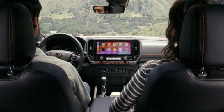 2026 Nissan Frontier interior view looking forward between 2 occupants showing 12.3 screen