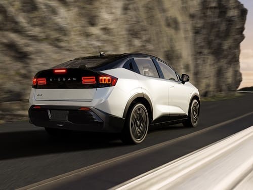 2026 Nissan LEAF in white 3/4 rear view driving on curved road at sunset