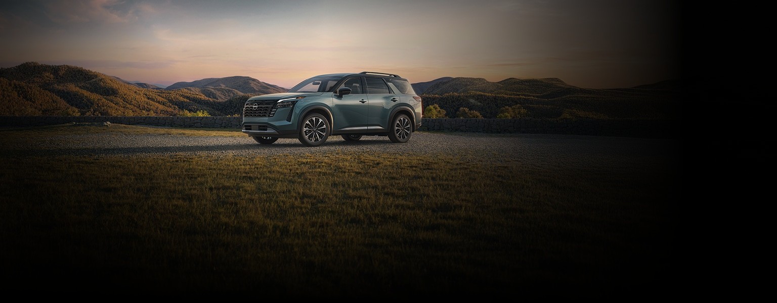 2026 Nissan Pathfinder parked on a dirt clearing with mountain peaks visible in the distant background.