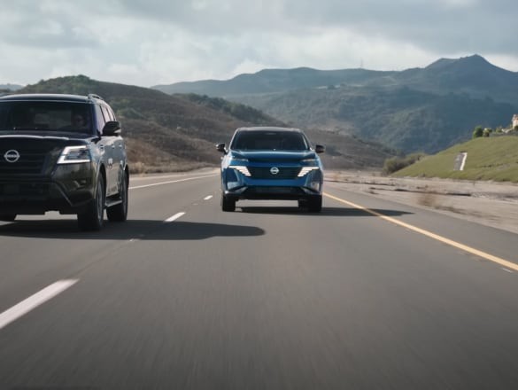 2027 Nissan Murano driving on rural road next to an SUV with hills in background